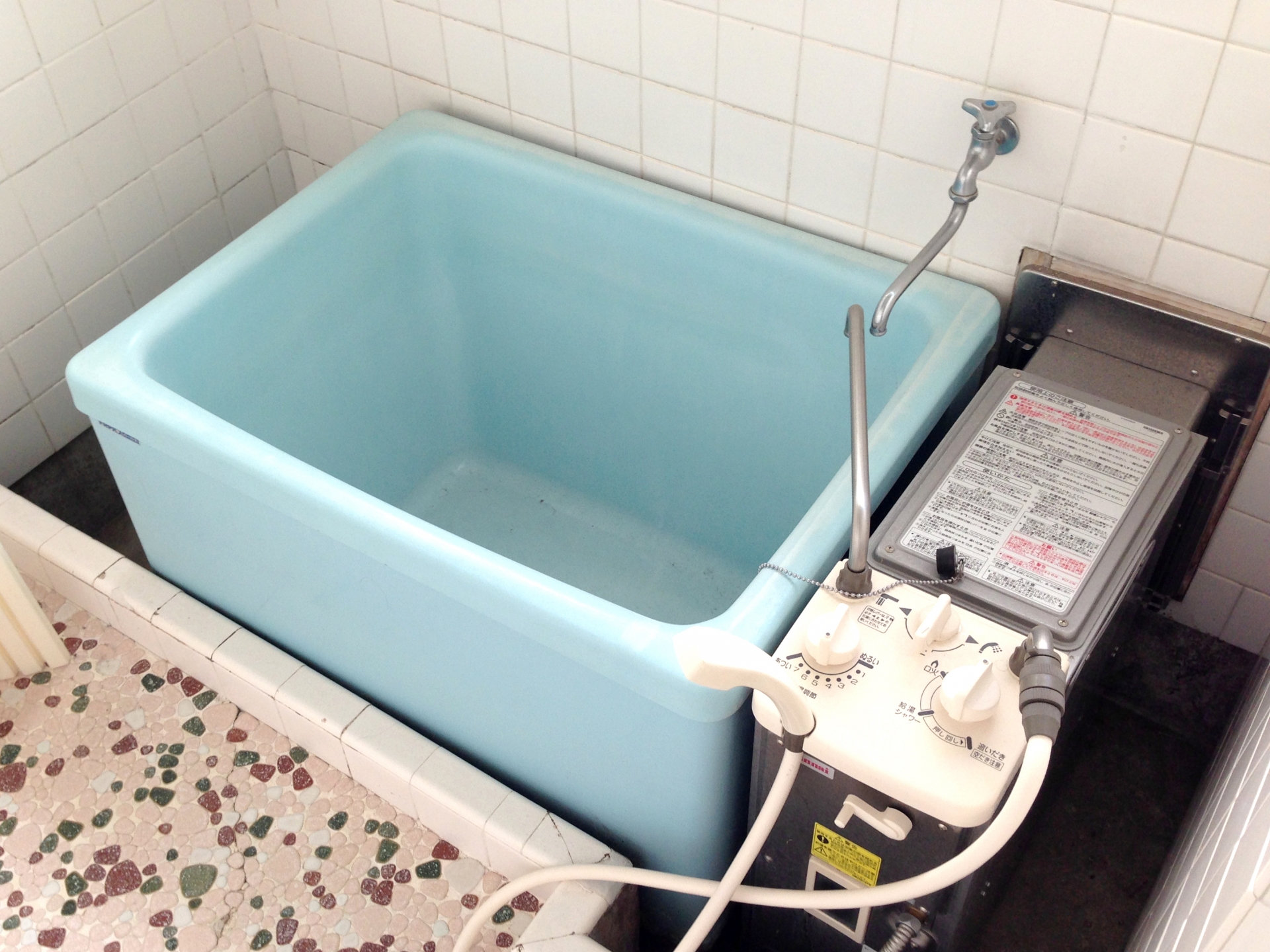 浴室に設置されたブルーの浴槽と横に配置された旧型風呂釜。