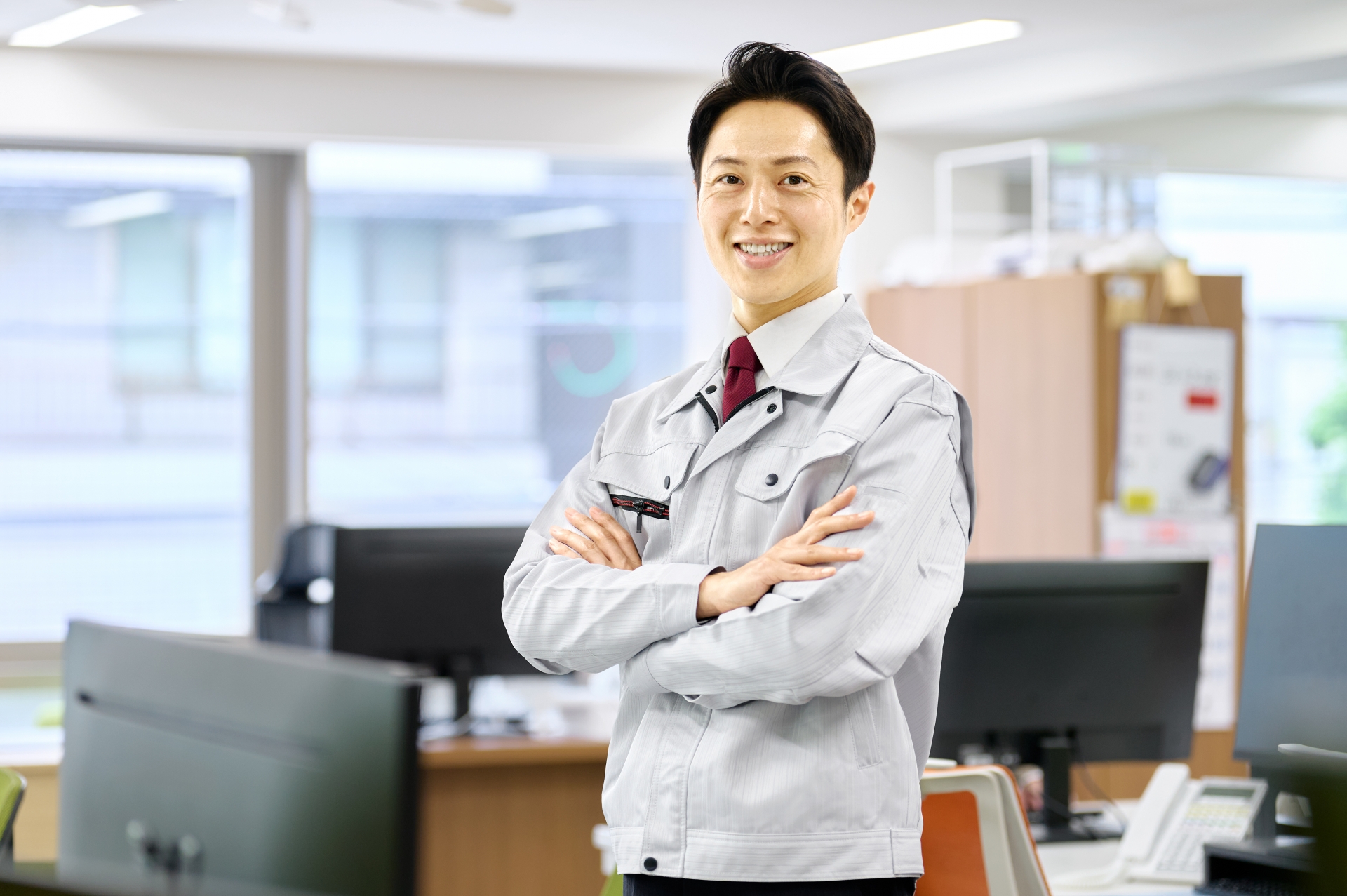 真剣な表情でカメラを見つめる作業服姿の男性スタッフ。給湯器交換の専門業者として、お客様に安心と信頼を届ける様子を表しています。