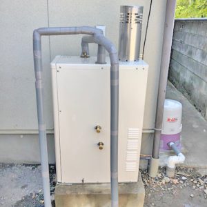 交換前の古いノーリツ製石油給湯器 OTQ-4034A。屋外に設置されている。